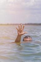 Die Hand des rechten Mannes gibt ein Zeichen für Hilfe aus dem Wasser foto