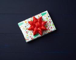 Geschenk verpackt in mehrfarbigem Papier auf blauem Holzhintergrund foto