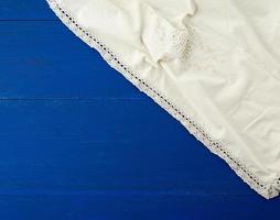 Weißes Küchentextiltuch gefaltet auf einem blauen Holztisch foto