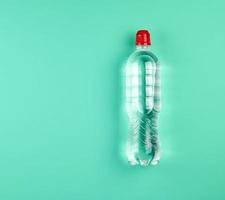 transparente Plastikflasche mit frischem Wasser auf grünem Hintergrund foto