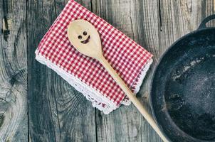 schwarze gusseiserne Bratpfanne mit Holzspatel zum Umrühren foto