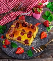 Käsekuchen mit Erdbeeren auf einer schwarzen Graphitplatte foto