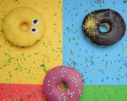 Runde verschiedene Donuts mit Streuseln auf einem hellen, mehrfarbigen Hintergrund foto