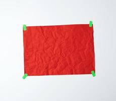 leeres rotes zerknittertes blatt papier, das mit grünen klebrigen papierstücken beklebt ist foto