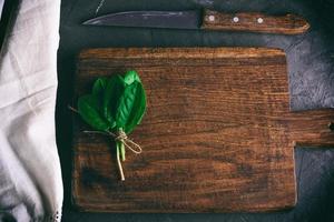 altes braunes Holzschneidebrett mit Griff und Bündel mit grünen Sauerampferblättern foto
