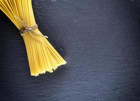rohe Spaghetti mit einem Seil auf einem schwarzen Hintergrund gebunden foto