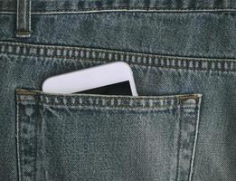 Smartphone-Fragment ist aus der Tasche alter Jeans zu sehen foto