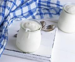 hausgemachter Joghurt in einem Glasgefäß auf einem weißen Holzbrett foto