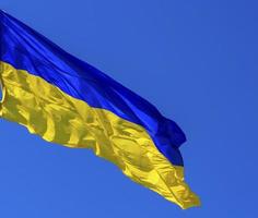 Textilflagge der Ukraine entwickelt sich vor einem strahlend blauen Himmel foto