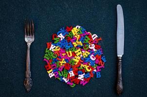 viele holzbuchstaben des englischen alphabets zwischen gabel und messer foto