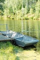 Ein altes Boot mit Rudern auf einem grünen Teich vor dem Hintergrund eines Waldes. foto