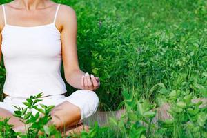 Yogafrau, die im grünen Gras sitzt foto