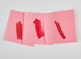 Abstriche von rotem Lippenstift auf einem rosa Papieraufkleber foto