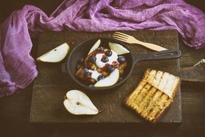 French Toast mit Beeren, Sirup und Sauerrahm in einer schwarzen gusseisernen Bratpfanne foto