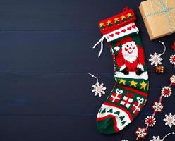 helle gestrickte Weihnachtssocke und -dekor auf einem blauen hölzernen Hintergrund foto