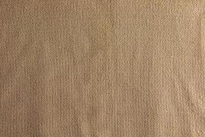 Beige gestrickter Teppich aus nächster Nähe. Textilstruktur auf beigem Hintergrund. detaillierter hintergrund aus warmem garn. natürlicher Wollstoff, Pulloverfragment. foto