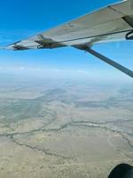 Blick aus einem Flugzeug auf die Tragfläche und die Savanne in Kenia darunter. foto