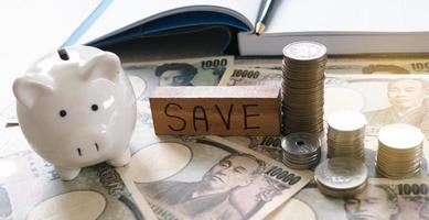Arbeitstisch mit Yen und Münzen mit Notizbuch, Einnahmen und Ausgaben. Geld sparen Konzept foto