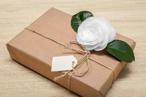 Geschenkbox mit leerem Etikett und weißer Blume foto