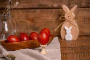 auf einem hölzernen hintergrund ostereier, bemalt mit natürlichen pflanzenfarben, zwiebelschalen, neben einem hölzernen osterhasen und einer weide foto