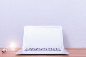 Laptop und Glühbirne auf dem Schreibtisch foto
