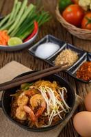 Pad Thai Shrimps in einer schwarzen Pfanne mit Eiern und Gewürzen foto