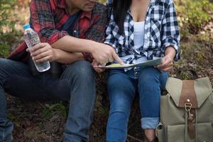 junges Paar, das Karte beim Wandern im Wald betrachtet foto