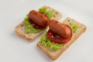 Wurst mit Tomaten und Salat auf Brot foto