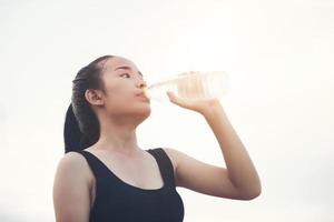 Trinkwasser des jungen Fitness-Teenagers nach laufender Übung foto
