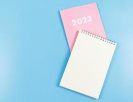 Flaches Notizbuch aus leerem Papier auf rosafarbenem Tagebuch 2023 auf blauem Hintergrund. foto