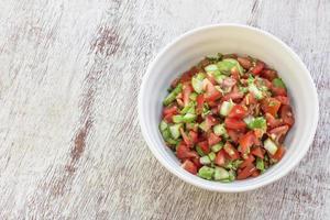 Gesundes Essen Tomaten-Gurken-Salat in Schüssel auf weißem Holzhintergrund. foto