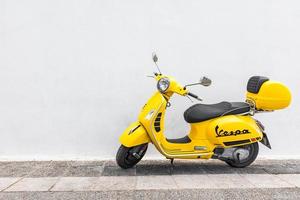 09.10.19 - santorini, griechenland gelber vespa-parkplatz an der holzwand des restaurants. der ikonische italienisch designte scooter. Roller steht auf der leeren Straße der alten Mittelmeerstadt foto