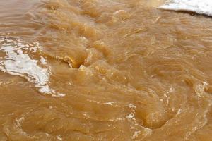 schlammiges Flusswasser. Frühjahrshochwasser. schmutziges schlammiges wasser mit whirlpool und weißer schaumnahaufnahme. foto