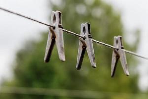 Wäscheklammern, die an einem Seil hängen. An einer Wäscheleine hängen drei Wäscheklammern. unscharfer Hintergrund. foto