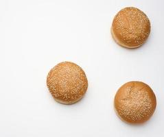 gebackenes rundes frisches weißes Weizenmehlbrötchen, bestreut mit Sesamsamen auf einem weißen Tisch. Hamburger, Cheeseberger und Sandwichbrötchen foto