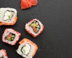 California-Sushi mit rotem Tobiko-Kaviar und Philadelphia-Sushi-Scheiben auf schwarzem Schieferbrett foto