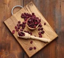 Haufen getrockneter Preiselbeeren in einem Holzlöffel auf einem braunen Tisch. köstliche Beere, Draufsicht foto