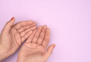 Zwei weibliche Hände falteten Handfläche an Handfläche auf einem violetten Hintergrund foto