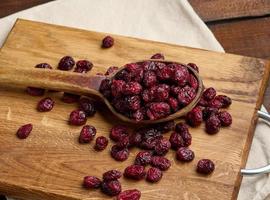 Haufen getrockneter Preiselbeeren in einem Holzlöffel auf einem braunen Tisch. köstliche Beere, Draufsicht foto