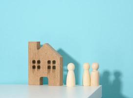 Familienfiguren aus Holz, Musterhaus auf blauem Hintergrund. immobilienkauf, mietkonzept. Umzug in neue Wohnungen foto