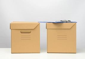Zwei Kartons aus brauner Wellpappe stehen auf einem weißen Tisch, Umzug, Warenanlieferung foto