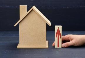 Holzhaus und eine weibliche Hand hält eine Stange mit einem roten Pfeil. immobilienwertsteigerungskonzept foto