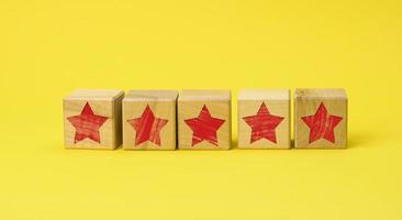 fünf Holzwürfel mit rotem Stern auf gelbem Grund. qualitätsbewertungskonzept, bewertung. bester Service und hohe Unternehmensbewertung foto