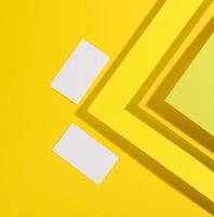 leere weiße rechteckige visitenkarte auf kreativem gelbem hintergrund aus papierbögen mit schatten foto