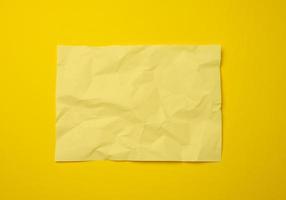 leeres, zerknittertes gelbes Blatt Papier auf gelbem Hintergrund foto