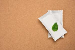 rechteckige weiße Pappteller und ein grünes Blatt auf braunem Korkhintergrund. kein plastikkonzept, draufsicht foto
