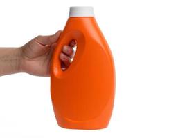 weibliche hand, die orangefarbene plastikflasche für flüssiges waschmittel hält foto