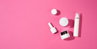 nagellack, glas und leere weiße plastikrohre für kosmetik auf rosa hintergrund. Verpackungen für Creme, Gel, Serum, Werbung und Verkaufsförderung foto