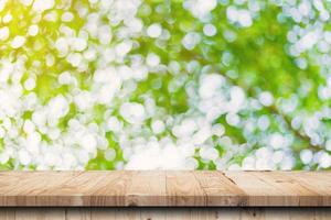 grünes blatt bokeh verschwommen und holztisch für naturhintergrund foto