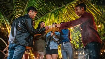 porträt glücklicher asiatischer freunde, die zusammen eine dinnerparty haben - junge leute, die biergläser abendessen im freien anstoßen - menschen, essen, trinken lebensstil, neujahrsfeierkonzept. foto